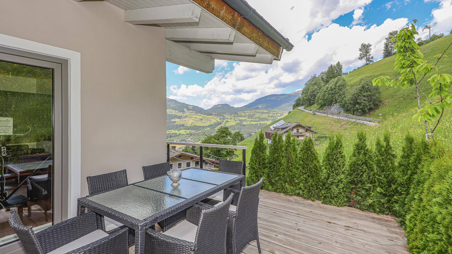 Sonniger Terrassenbereich mit Gartenmöbeln und weitem Blick auf die alpine Landschaft.