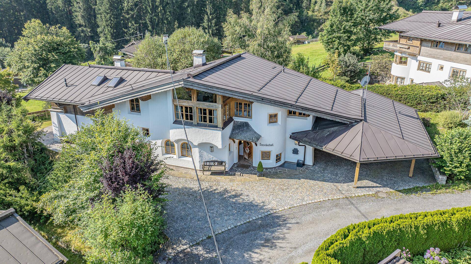 Luftaufnahme des Anwesens mit umliegender grüner Landschaft und Bergen.