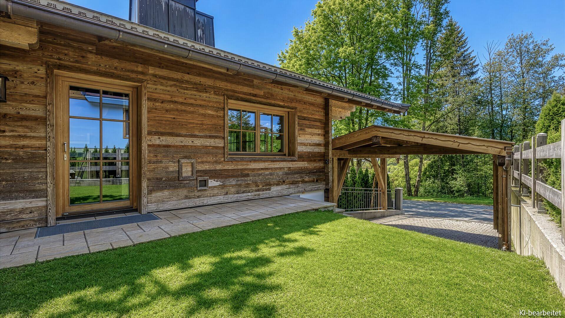 Holzhaus mit gepflegtem Rasen und überdachtem Carport, umgeben von grüner Natur und Bäumen.