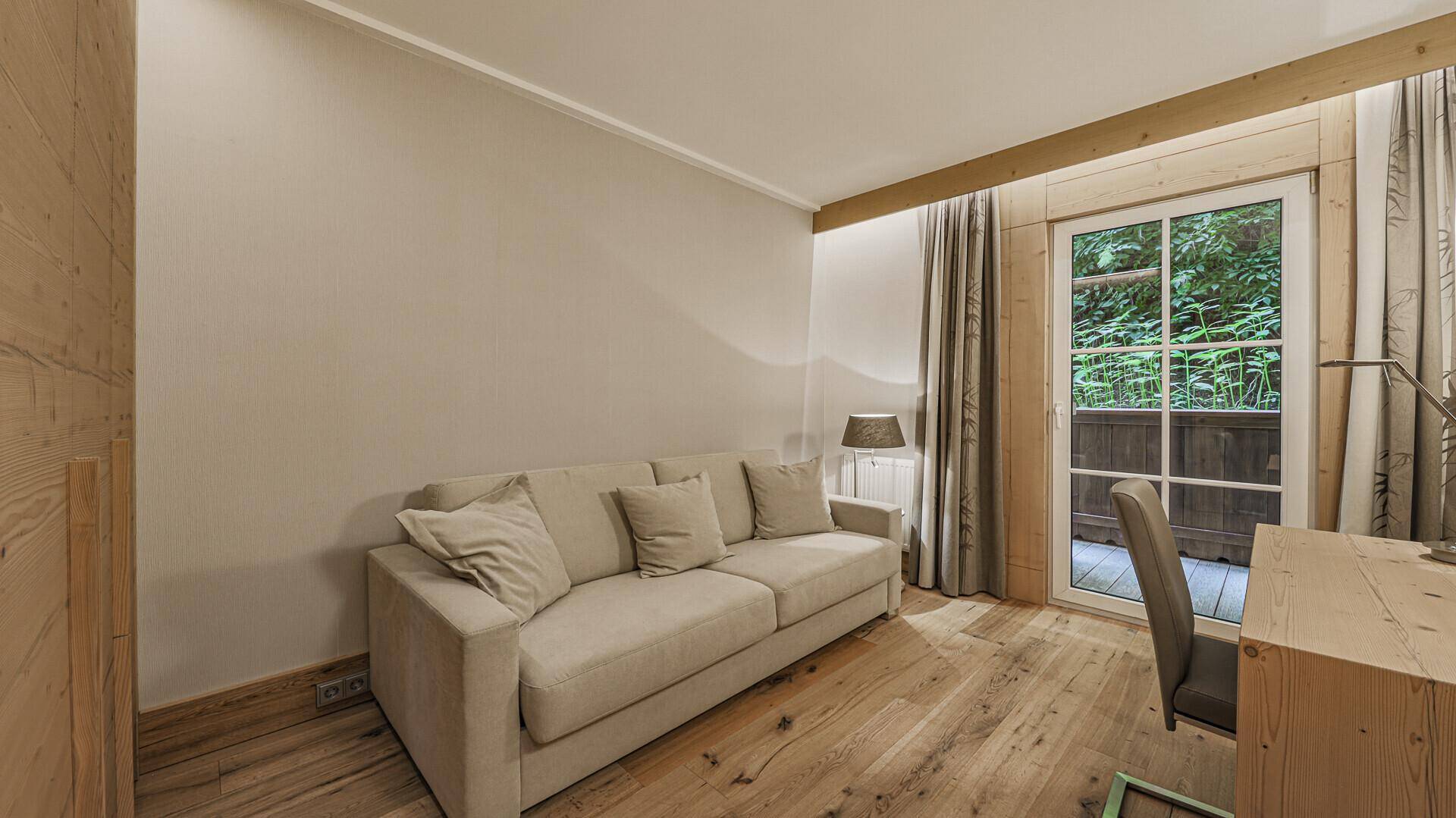 Gemütliches Zimmer mit Schlafsofa, Schreibtisch und Zugang zum Außenbereich.