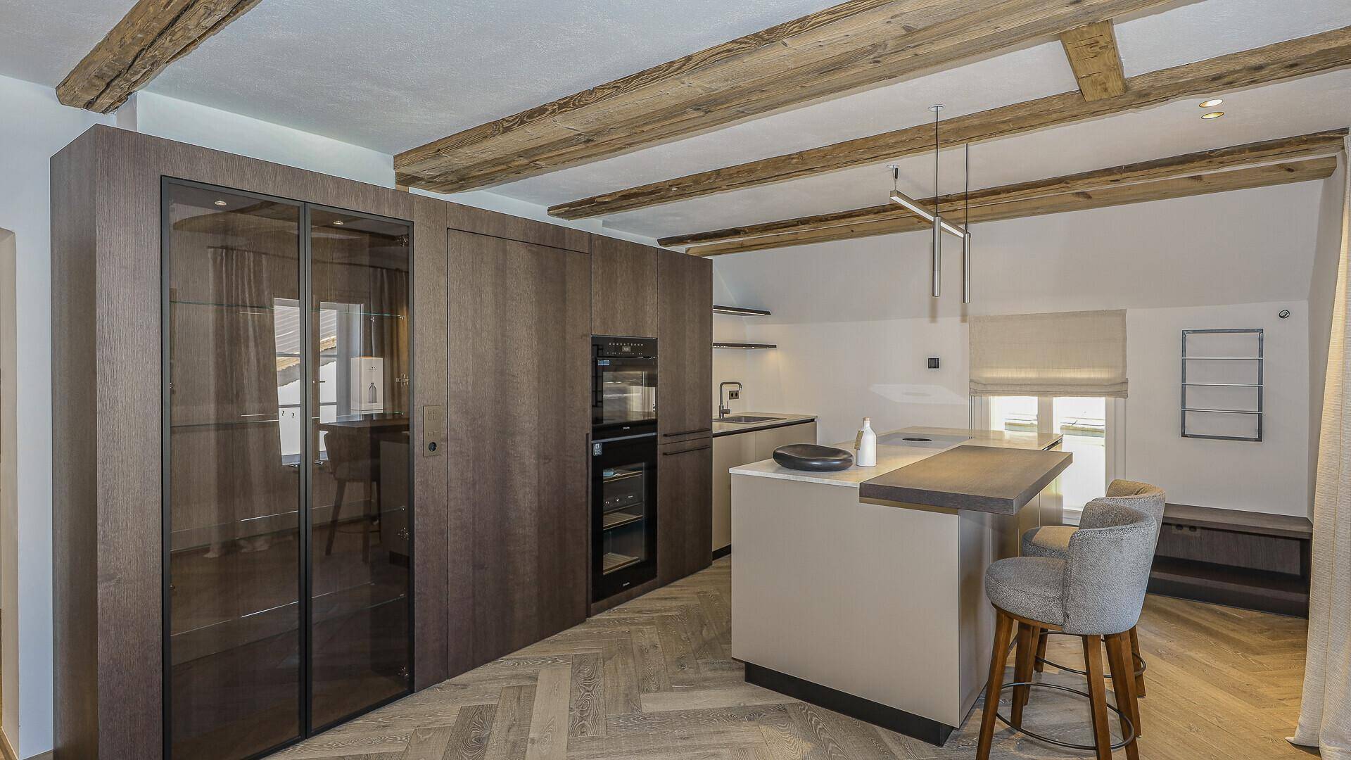 Stilvolle Küche mit dunklen Holzschränken, Kochinsel und integrierten Geräten.