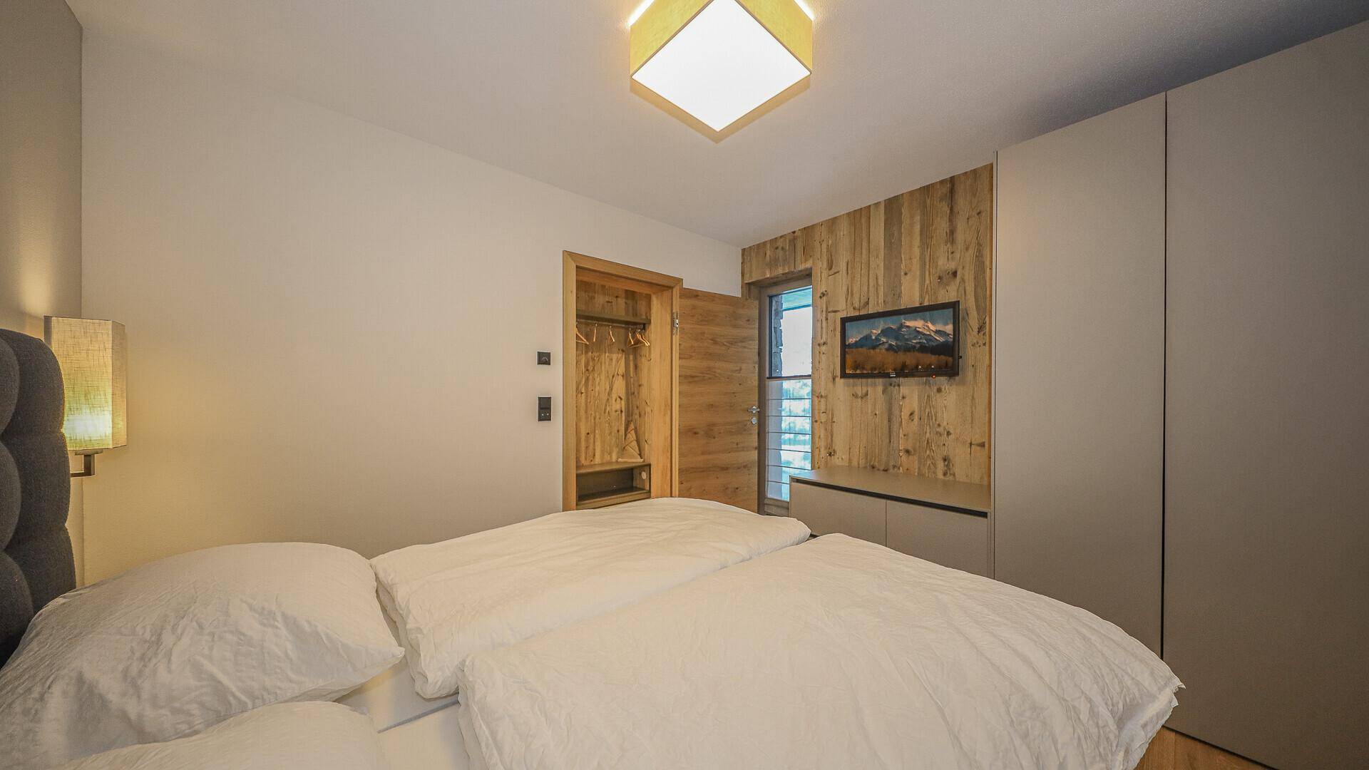 Helles Schlafzimmer mit Doppelbett, Holzakzenten und integrierten Kleiderschränken.