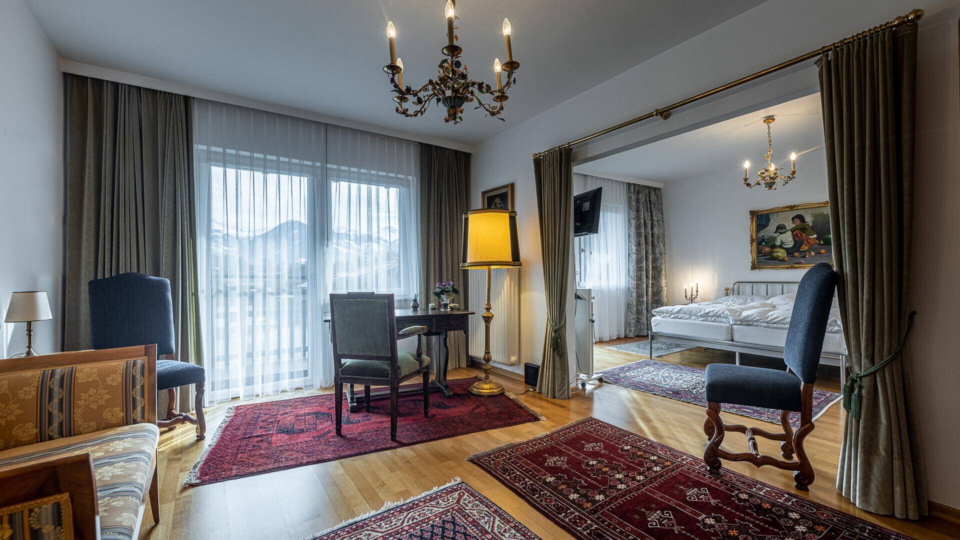 Geräumiges Schlafzimmer mit separatem Sitzbereich und Balkonzugang mit weitem Blick auf die Berge.