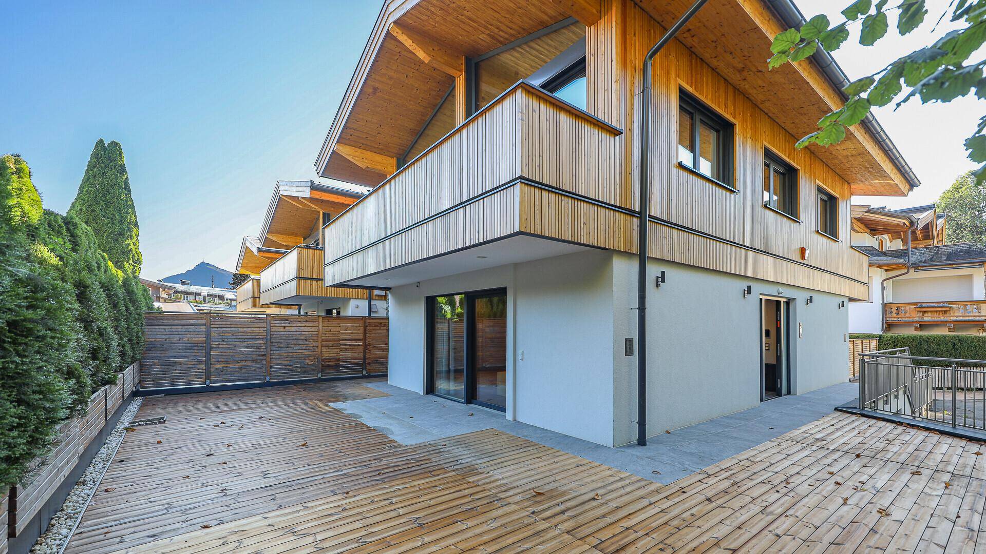 Moderne Holzfassade mit großzügiger Terrasse und Zugang zum Gartenbereich.