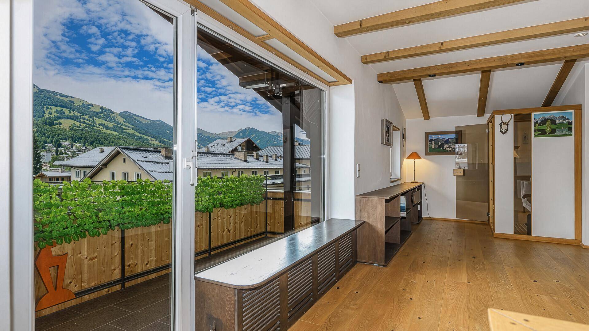 Heller Wohnbereich mit großem Fenster und Balkonzugang, bietet einen weiten Blick auf die Berge.