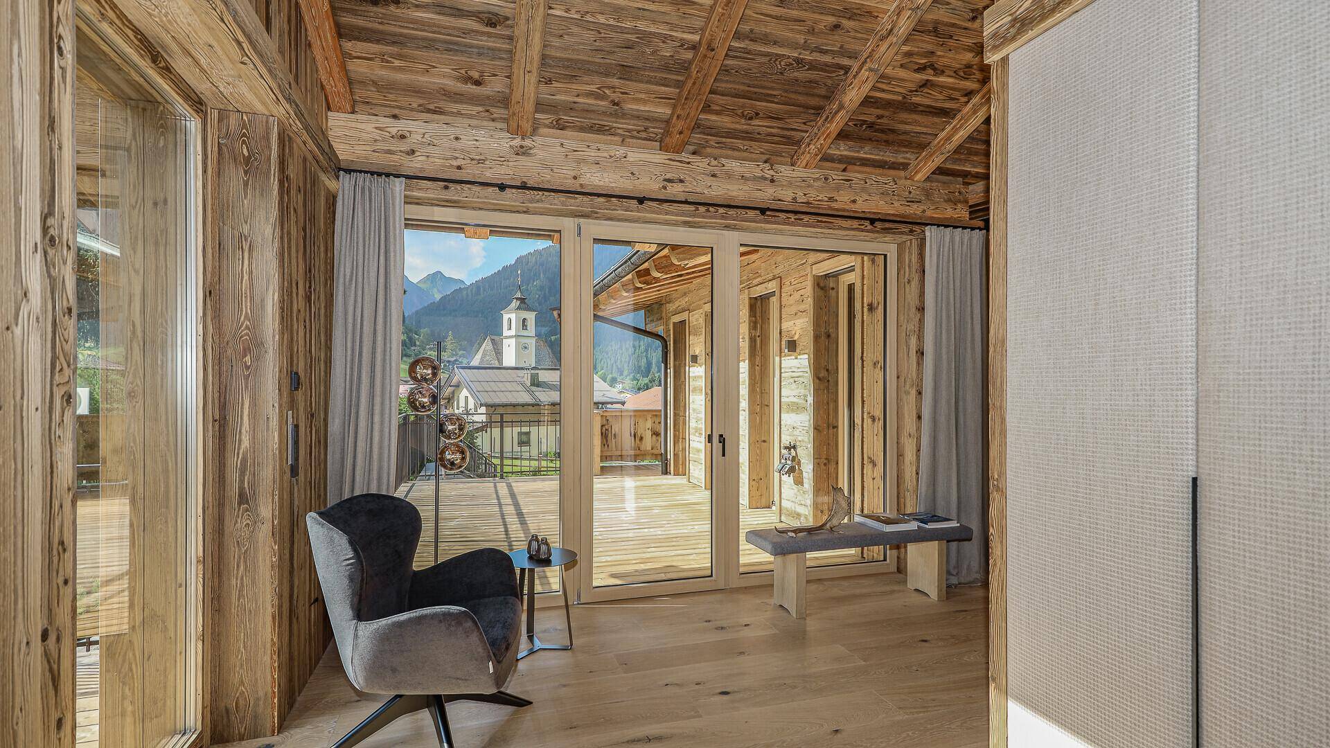 Helles Schlafzimmer mit Holzwänden, Holzbalkendecke und Zugang zu einer großen Terrasse.