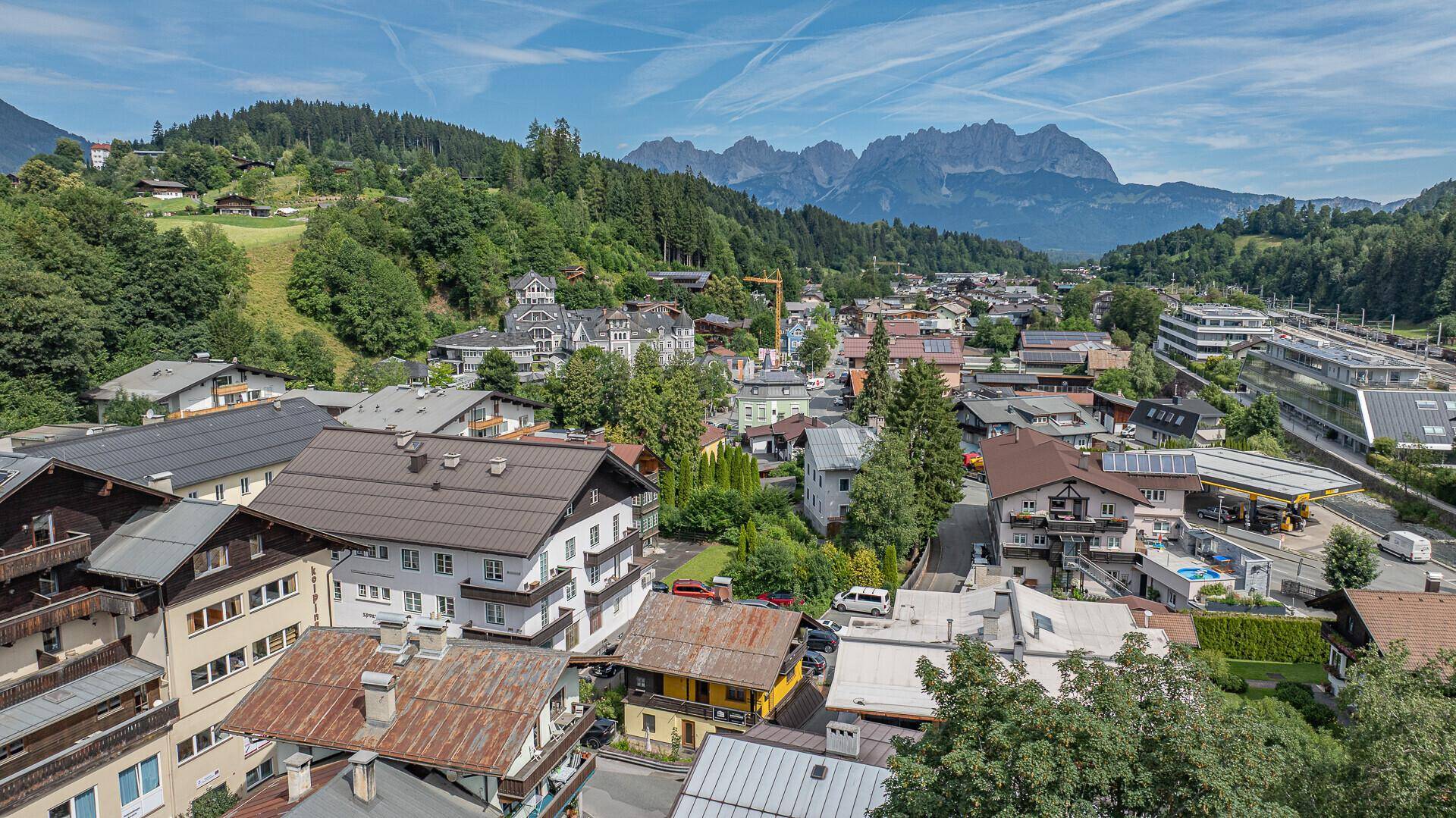 Panoramablick auf die Stadt mit traditionellen Gebäuden und majestätischen Bergen im Hintergrund.