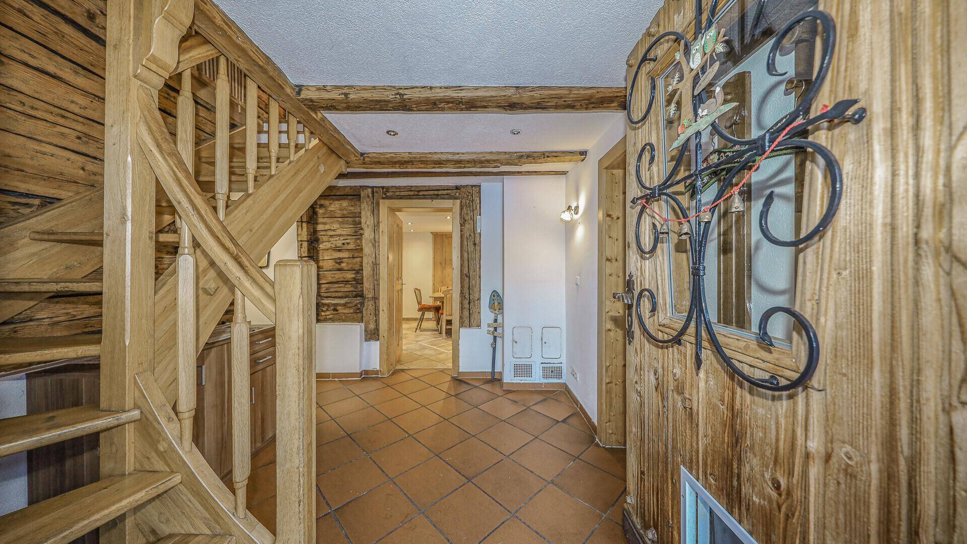 Geräumiger Flur mit Holztreppe und rustikalen Terrakotta-Fliesen, führt zu weiteren Räumen.