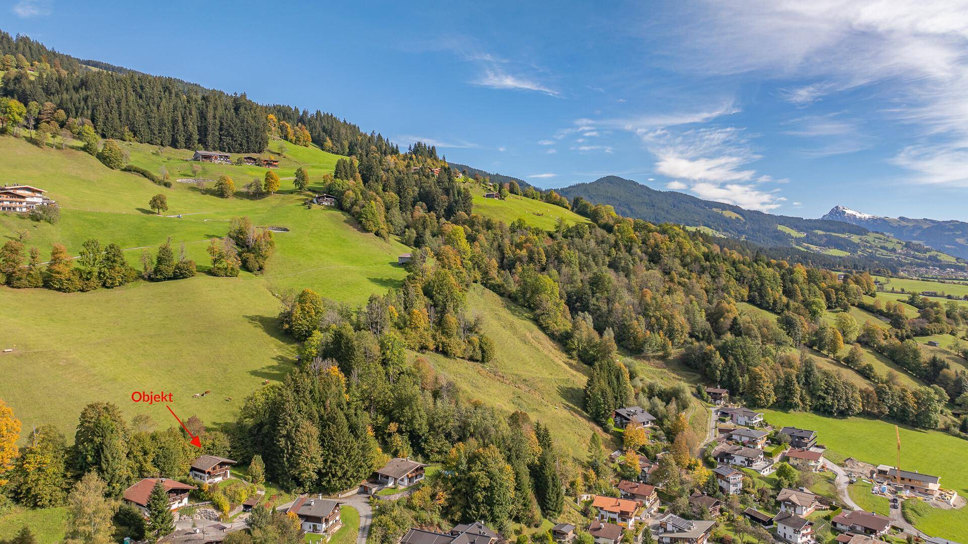 Weitläufige Luftaufnahme der Immobilie in einer idyllischen Berglandschaft mit grünen Wiesen.