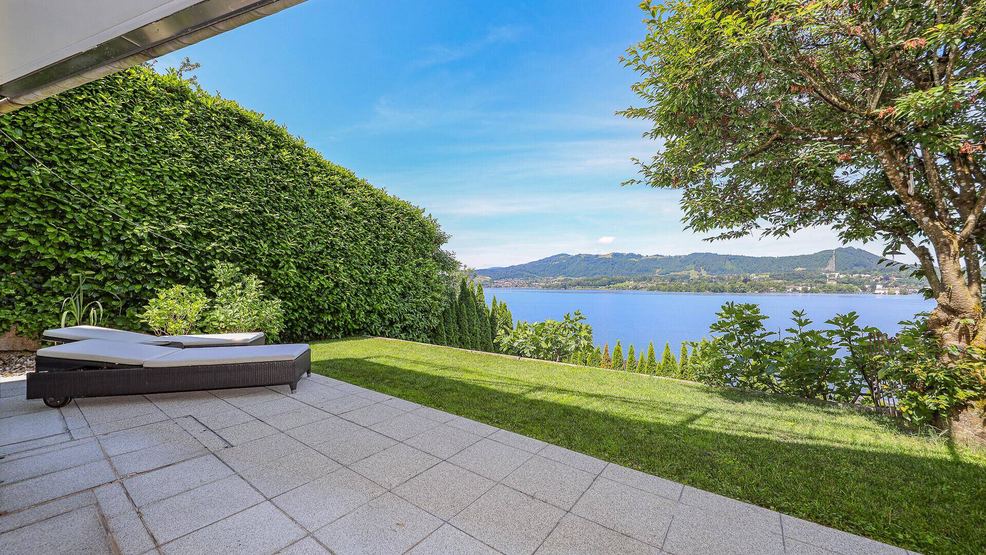 Idyllischer Gartenbereich mit Liegestühlen auf der Terrasse und einem atemberaubenden Seeblick.