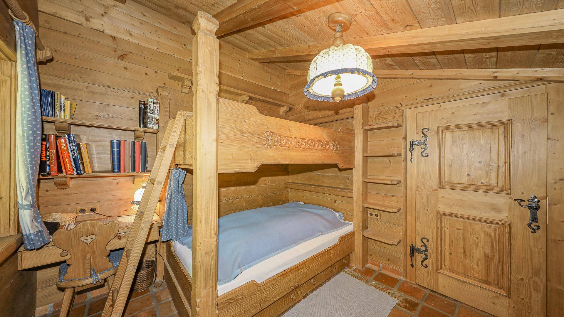 Gemütliches Kinderzimmer mit Etagenbett, Holzvertäfelung und einem kleinen Schreibtisch.