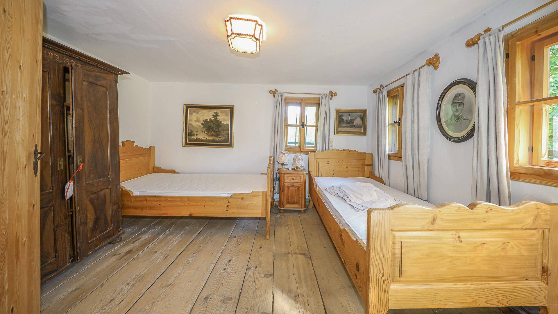 Geräumiges Schlafzimmer mit zwei traditionellen Holzbetten und rustikalem Holzboden.