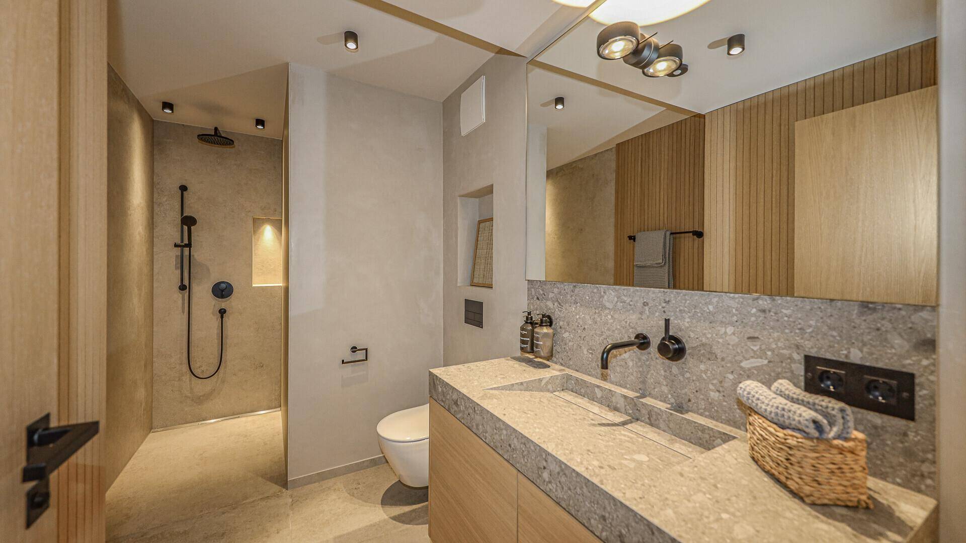 Modernes Badezimmer mit begehbarer Dusche, Einzelwaschbecken und eleganten Stein-Oberflächen.