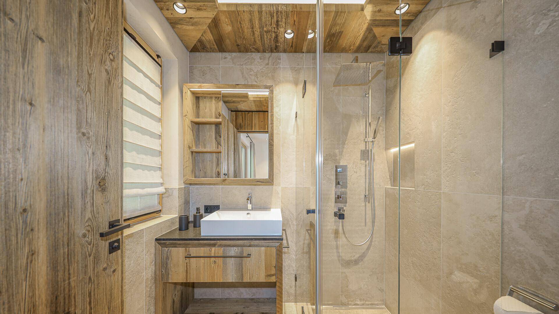 Modernes Badezimmer mit begehbarer Dusche, Einzelwaschbecken und Holzdetails.