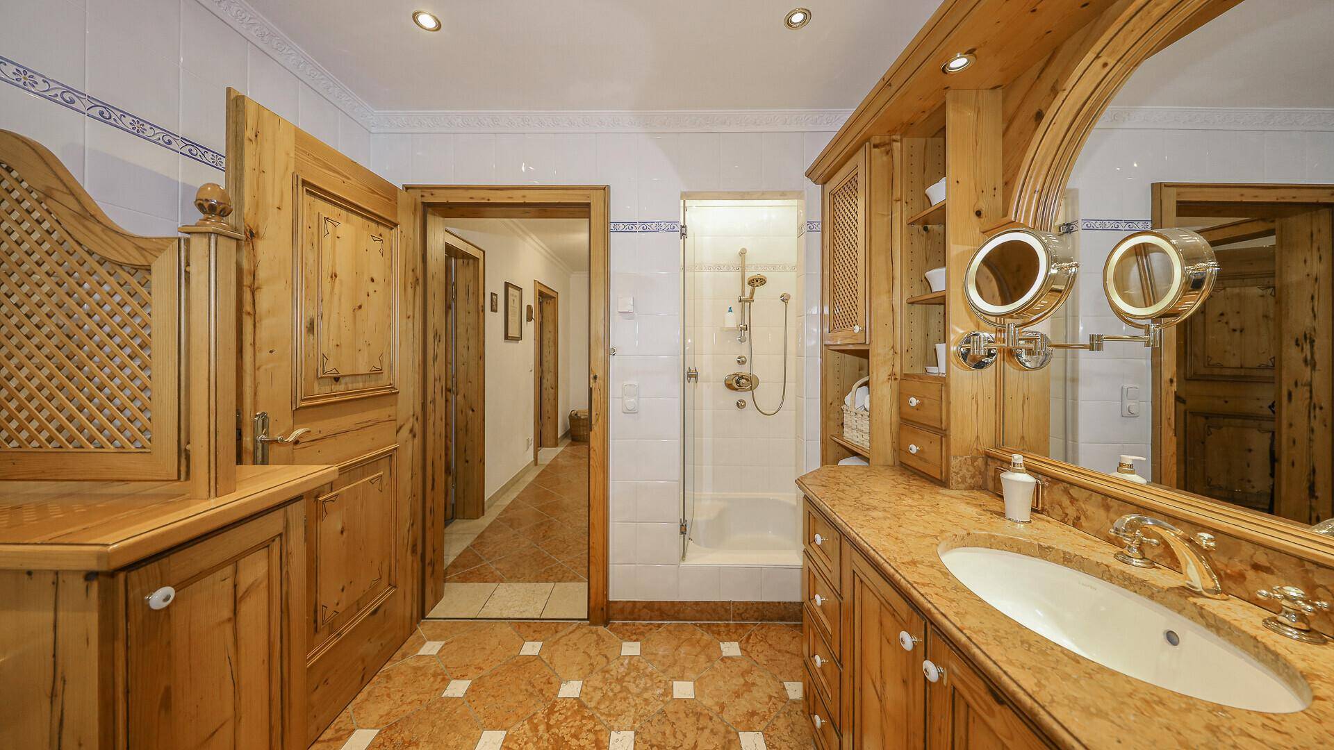 Rustikales Badezimmer mit Holzelementen, Einzelwaschbecken und einer modernen Duschkabine.