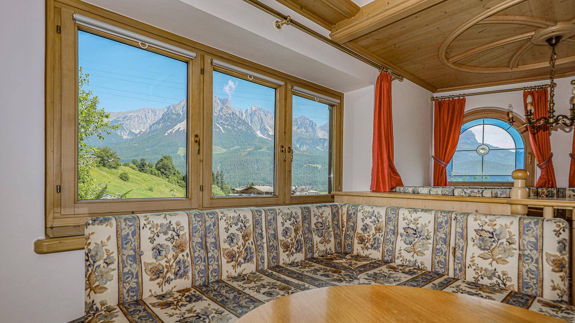 Gemütlicher Essbereich im alpinen Stil mit Eckbank und herrlichem Bergblick durch große Fenster.