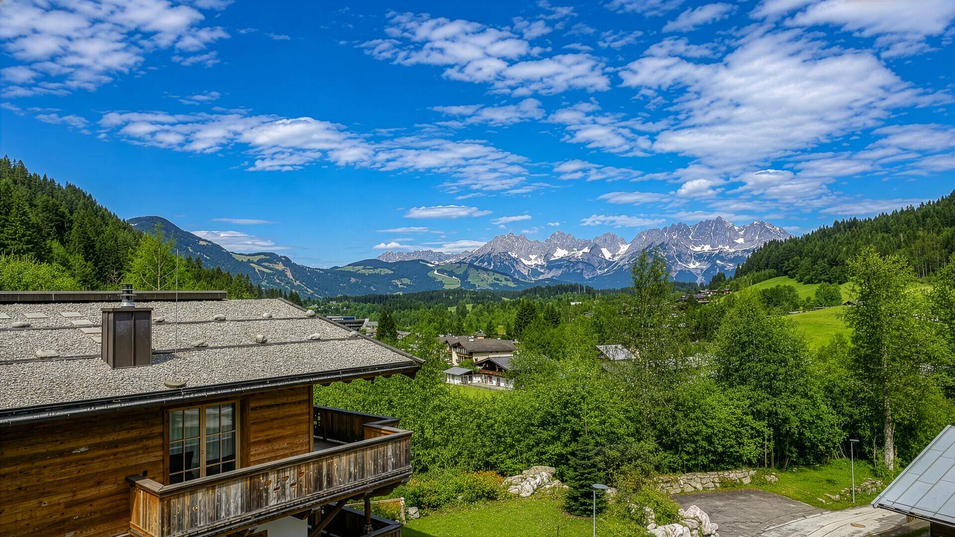 Malerische Berglandschaft mit traditionellen Häusern und üppiger grüner Natur unter blauem Himmel.