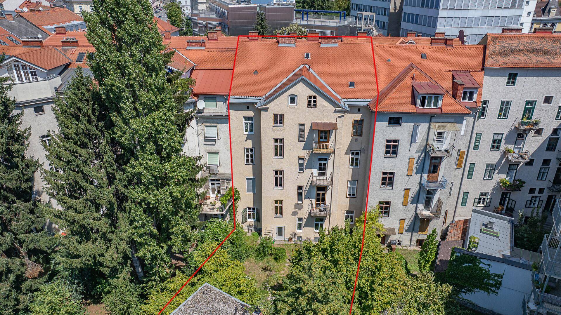 Rückansicht der Liegenschaft mit großem Gartenbereich und umliegenden Bäumen.