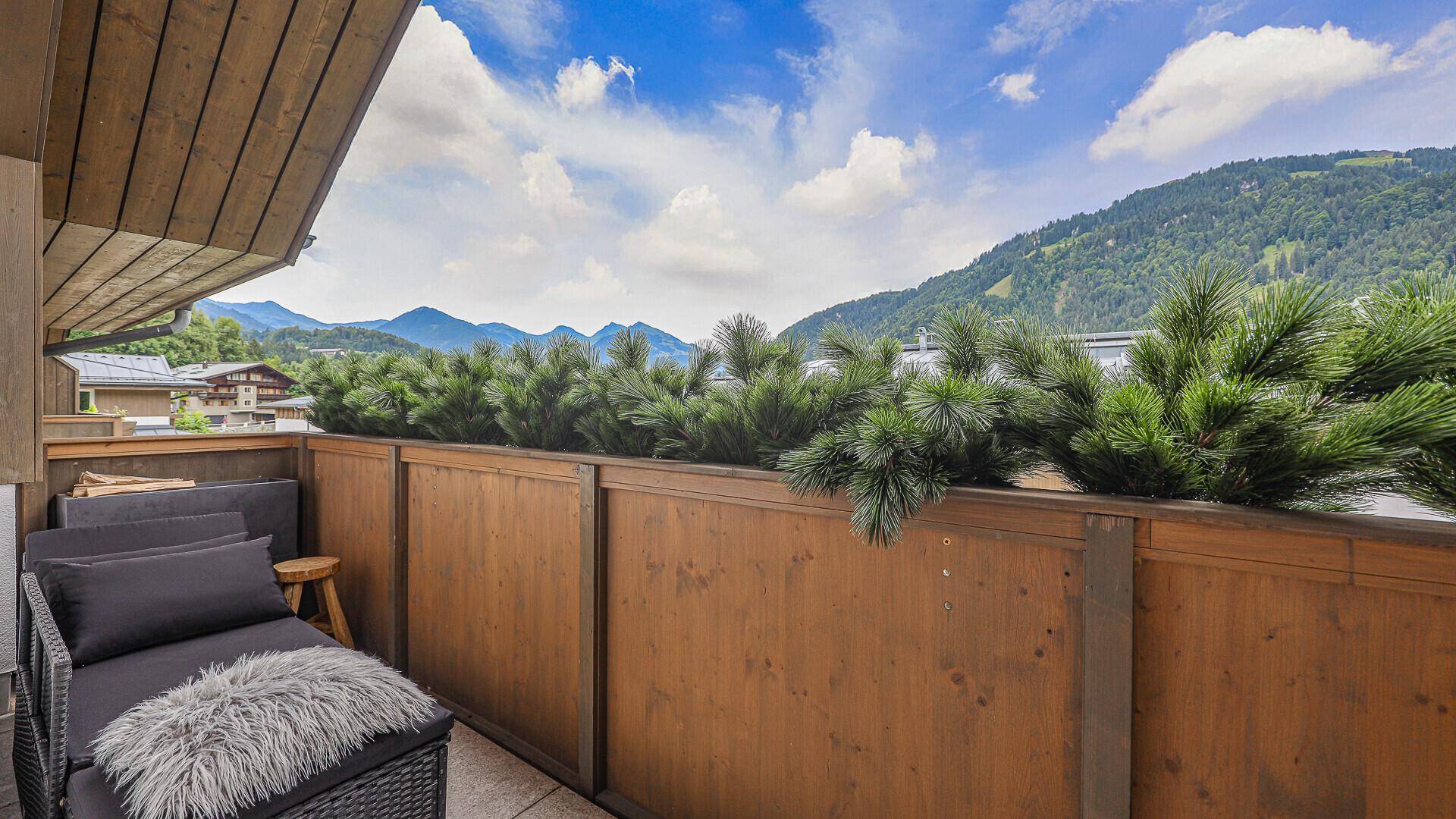 Geräumiger Balkon mit bequemen Sitzmöbeln und Panoramablick auf die umliegenden Berge.