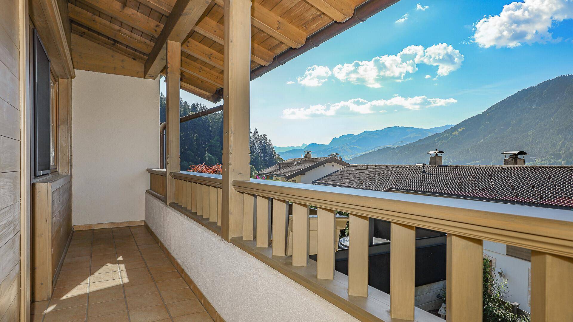 Überdachter Balkon mit Holzgeländer und atemberaubendem Panoramablick auf die Berge.