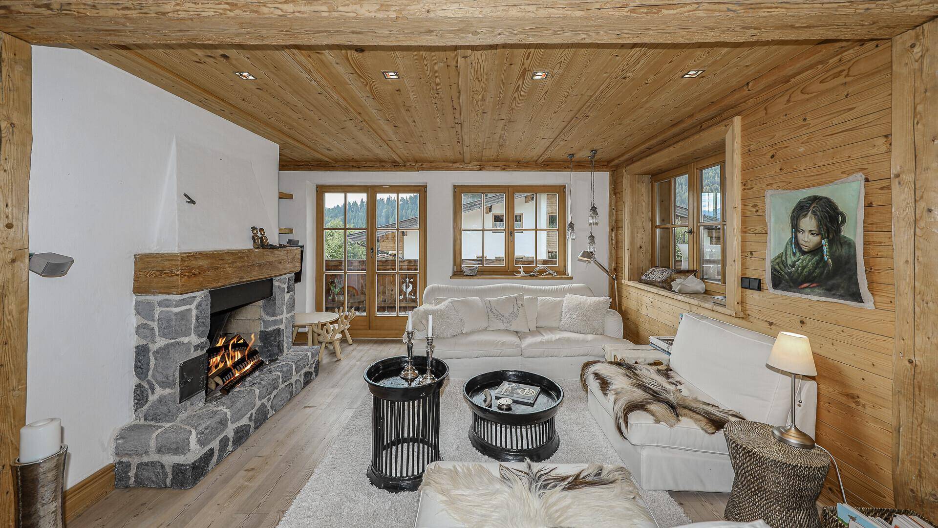 Gemütlicher Wohnbereich mit Kamin, Holzbalken und Blick auf die umliegende Natur.