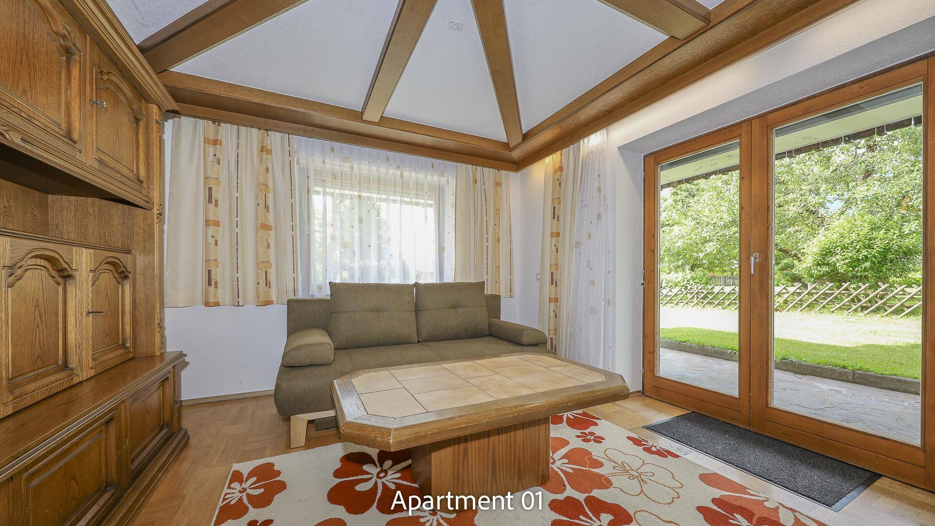 Gemütliches Wohnzimmer von Apartment 01 mit Sofa, Couchtisch und direktem Zugang zum Garten.