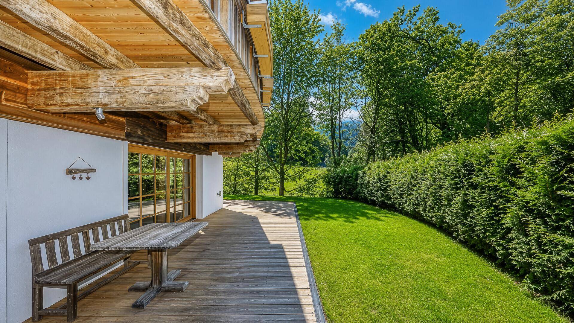 Holzterrasse mit Sitzgelegenheiten und Blick auf den gepflegten Garten.