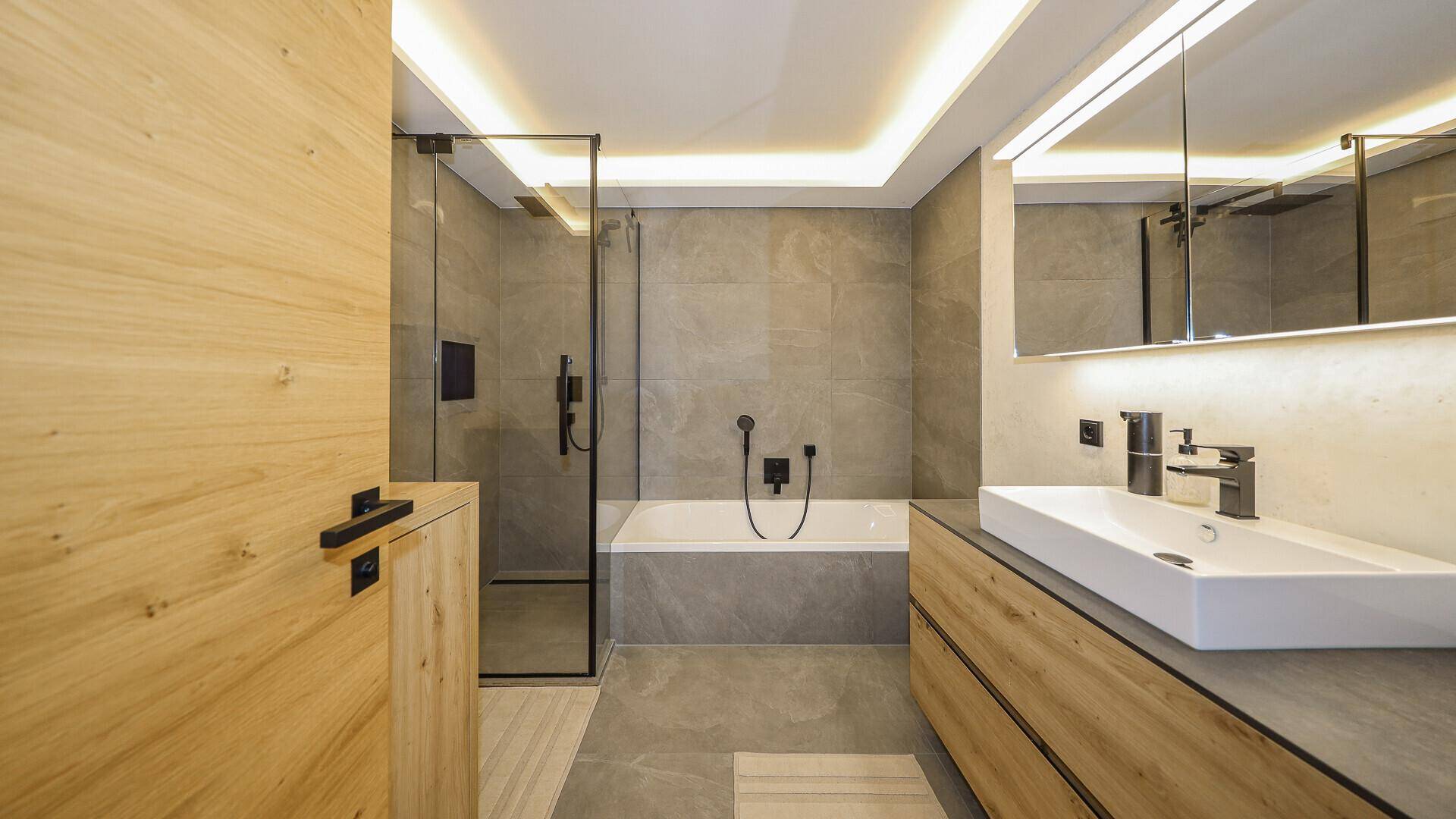 Modernes Badezimmer mit großformatigen Fliesen, Dusche und Badewanne.