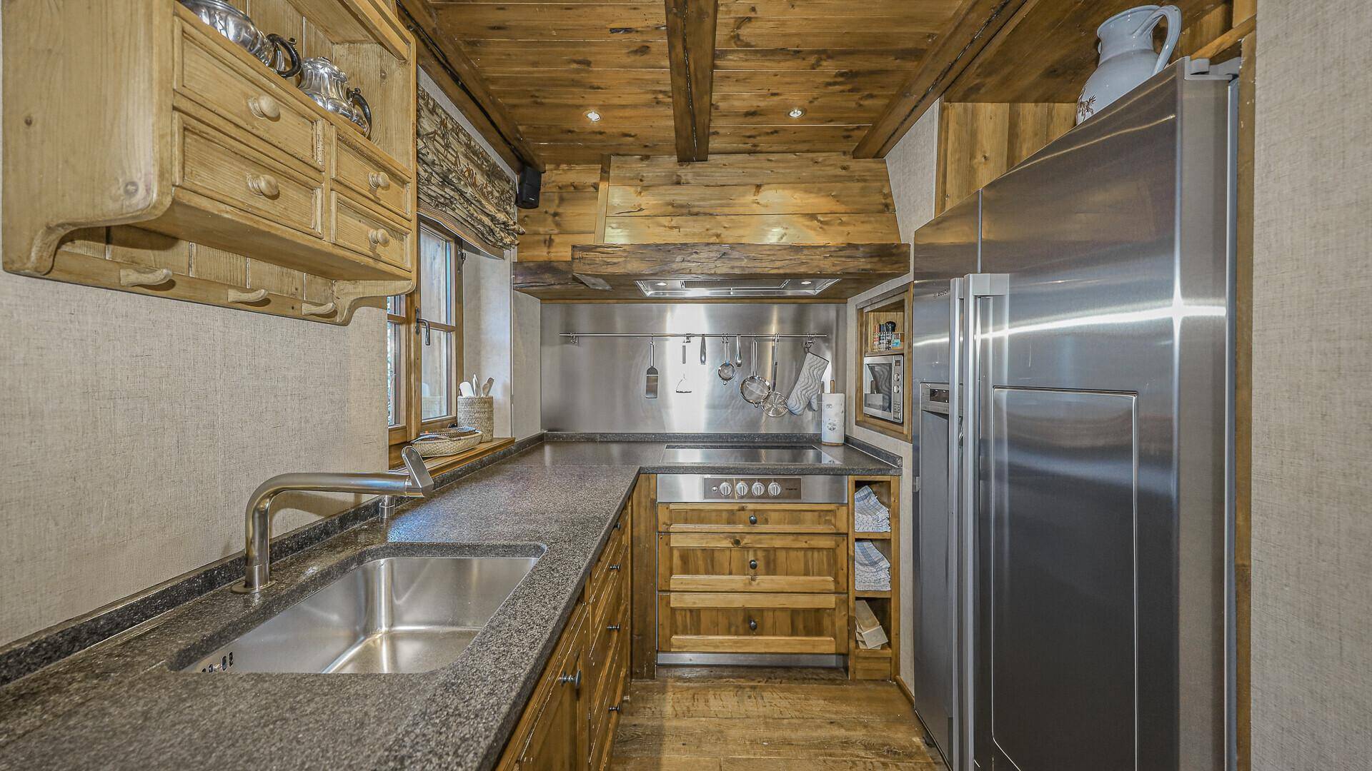 Funktionale Küche mit Granitarbeitsplatten, Edelstahlgeräten und Holzelementen im alpinen Stil.