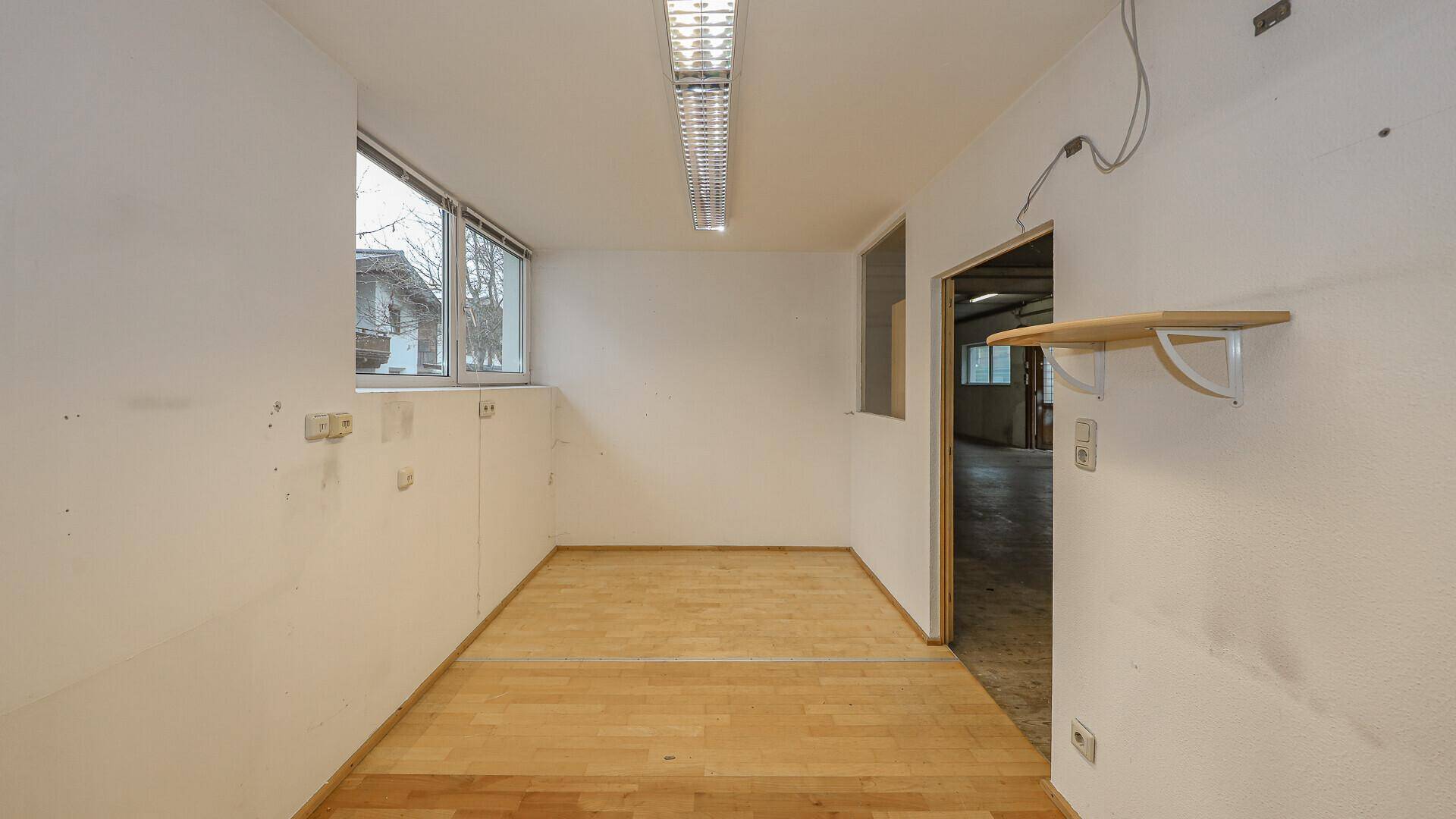 Heller Raum mit Holzfußboden und einem Fenster, geeignet als Büro oder kleiner Arbeitsbereich.