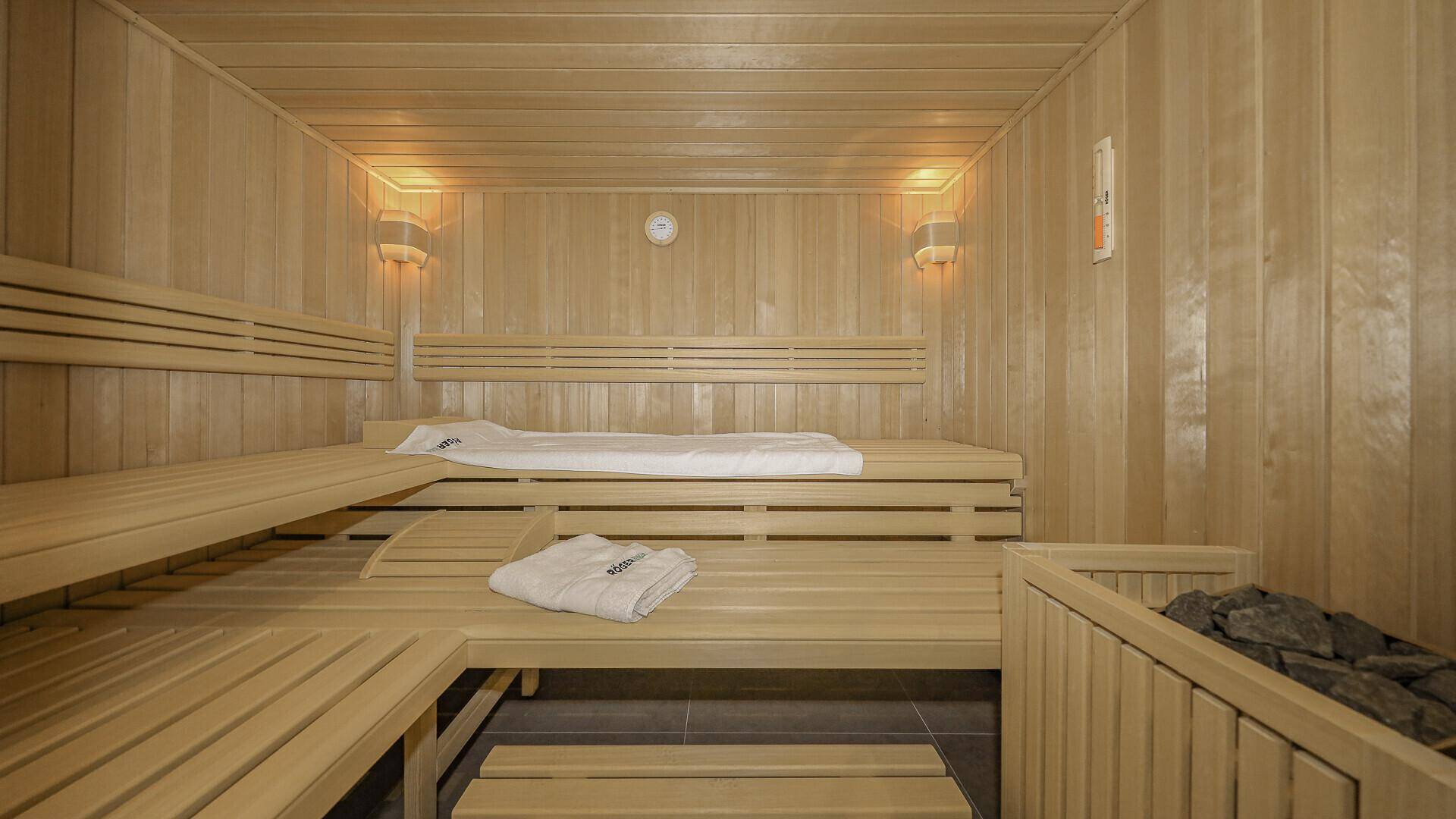 Traditionelle Holzsauna mit mehreren Bänken und Heizofen für Wellness.