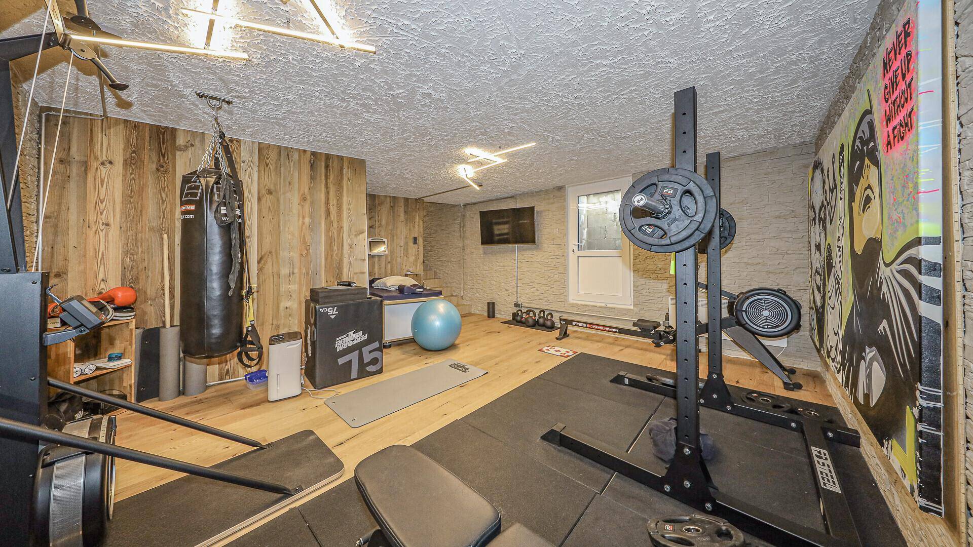 Geräumiger Fitnessbereich mit modernen Geräten, Holzverkleidung und vielseitigen Trainingsmöglichkeiten.