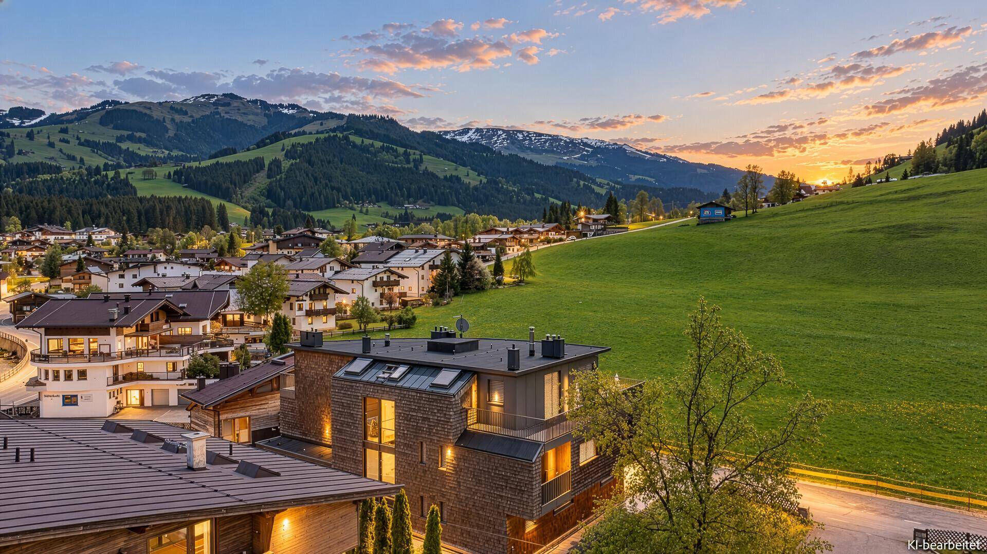 Sonnenuntergang über einer Wohnanlage in den Alpen mit weitem Bergblick.