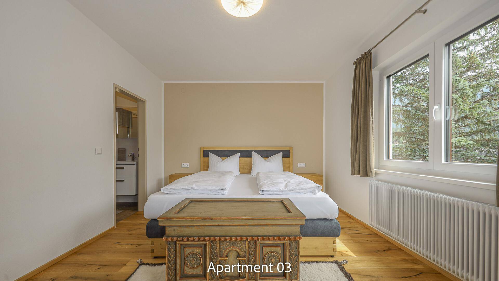 Helles Schlafzimmer von Apartment 03 mit großem Fenster und Zugang zum Badezimmer.