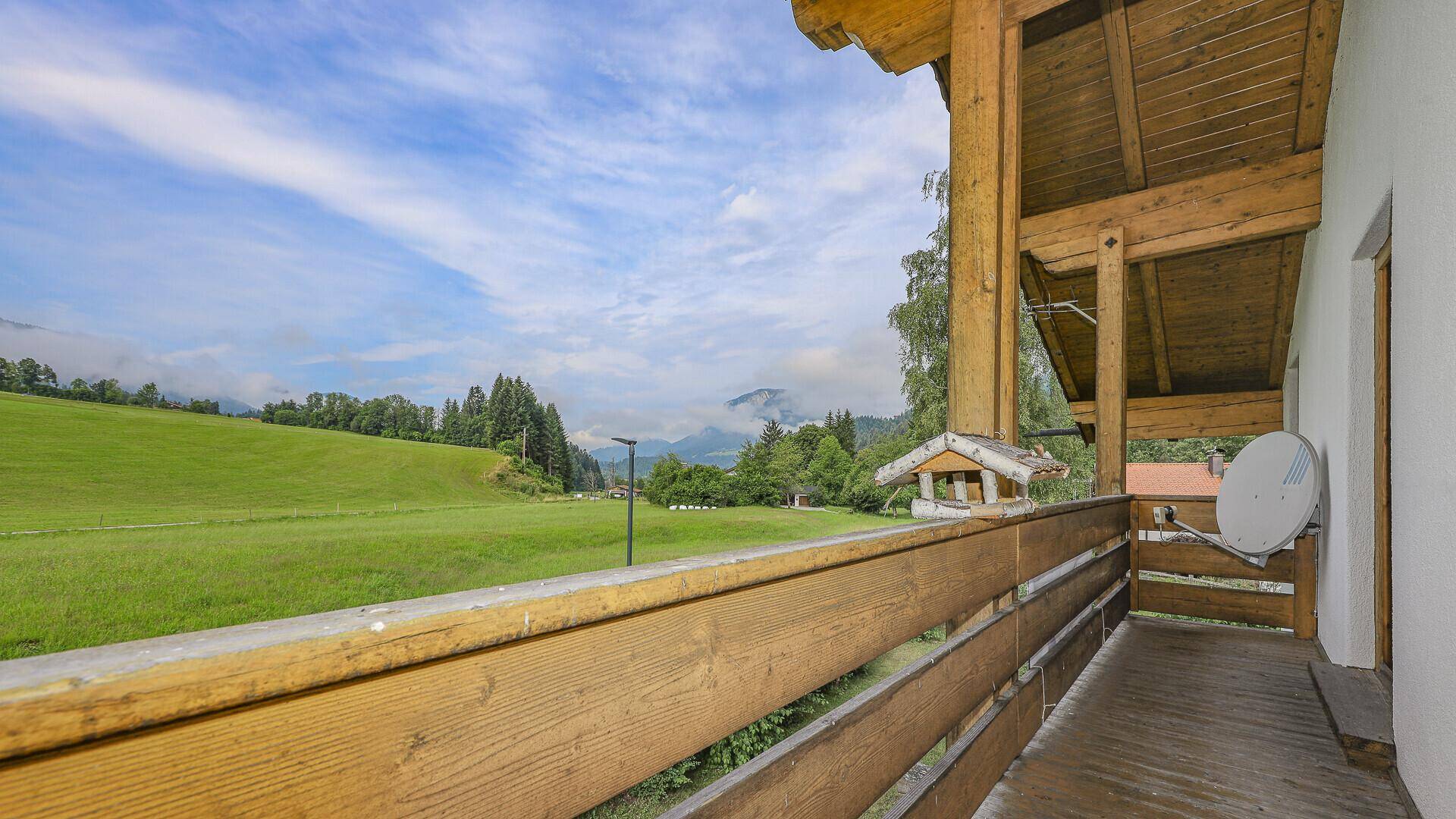Geräumiger Holzbalkon mit Panoramablick auf die umliegende Natur und die Berge.