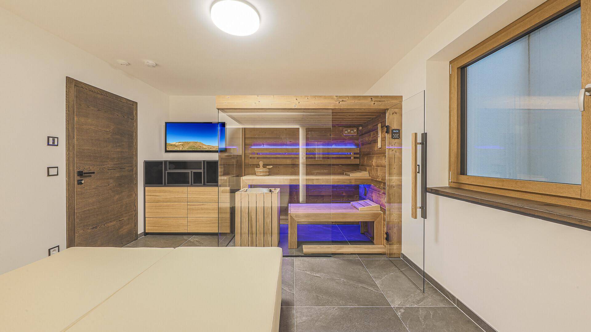 Entspannungsbereich mit moderner Sauna, Liegefläche und Fenster für natürliches Licht.