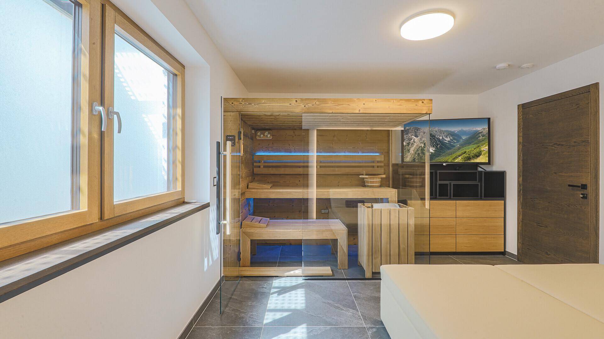 Moderner Wellnessbereich mit Sauna, Liegen und Fernseher, ideal zur Erholung.