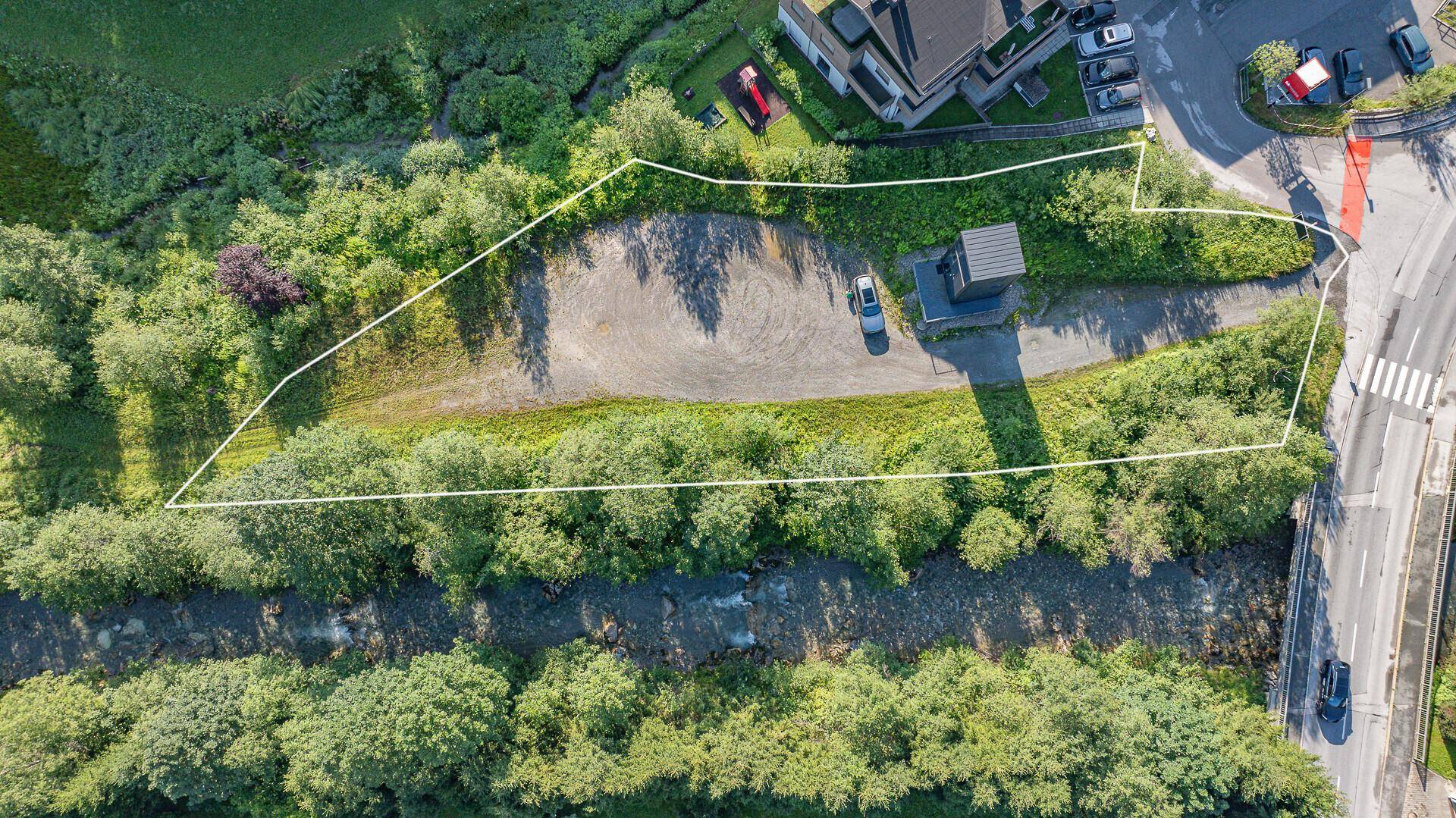 Vogelperspektive des umrandeten Grundstücks mit angrenzendem Fluss und einer Straße.