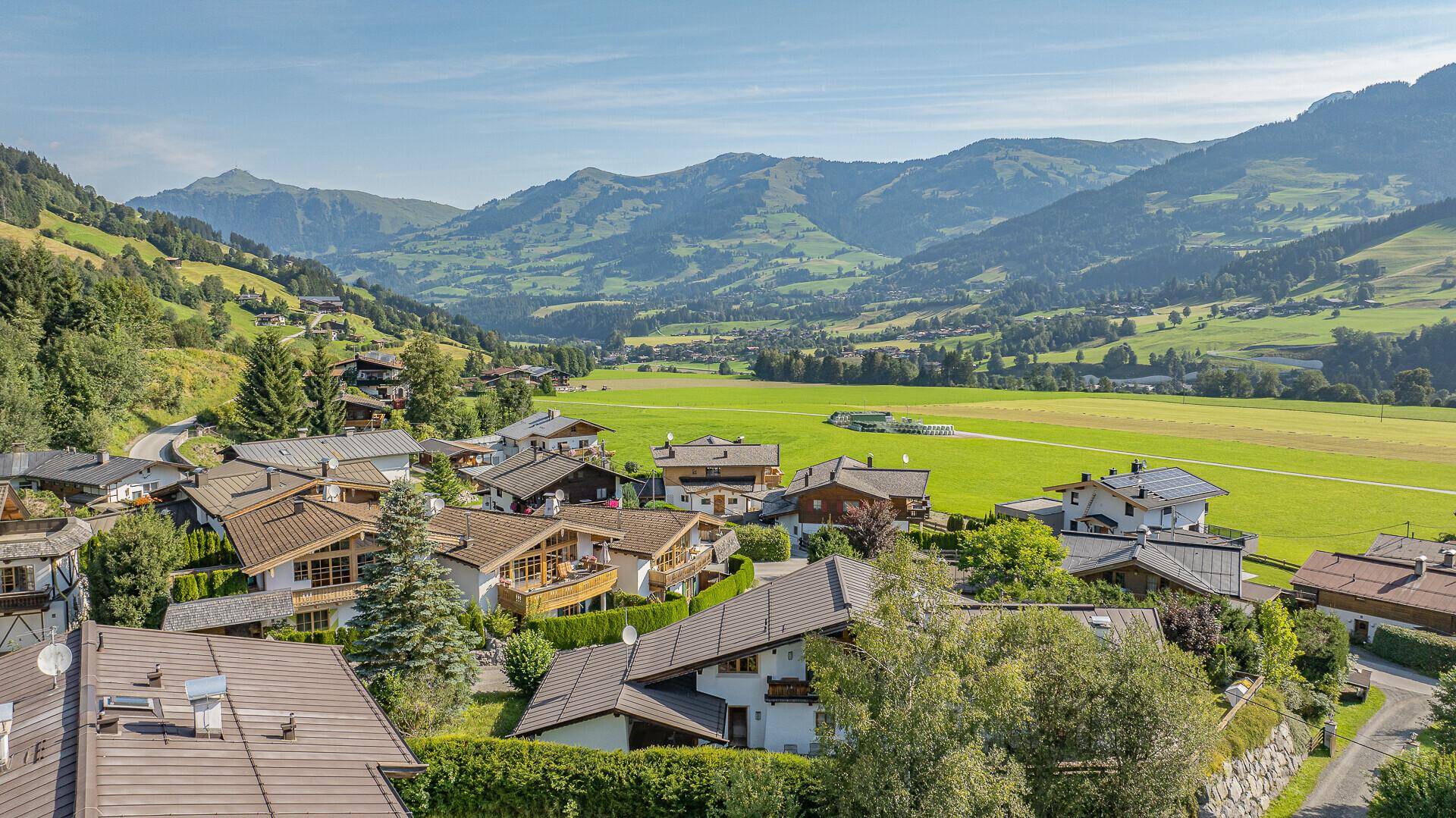 Panoramablick auf das grüne Tal und die umliegenden Berge mit Siedlung.