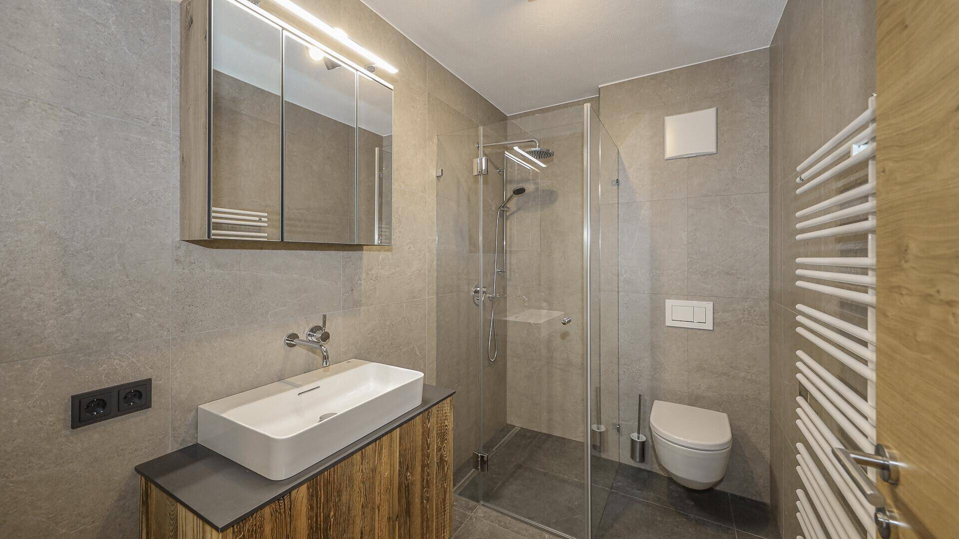 Modernes Badezimmer mit Dusche, Einzelwaschbecken, Wand-WC und Spiegelschrank.