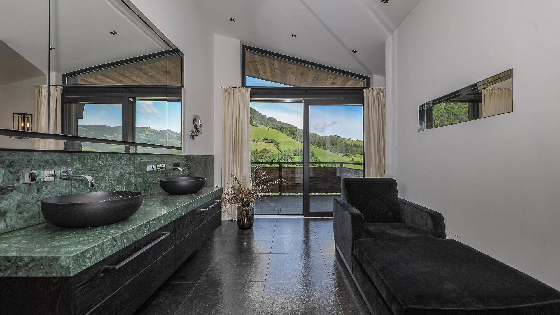 Modernes Badezimmer mit Doppelwaschbecken, grüner Marmorplatte und Bergblick.