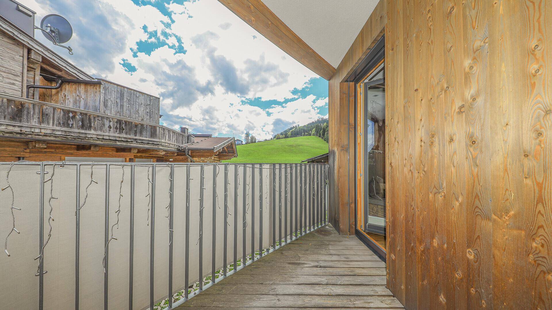 Kleiner Balkon mit Holzboden und Blick auf die grüne Berglandschaft.