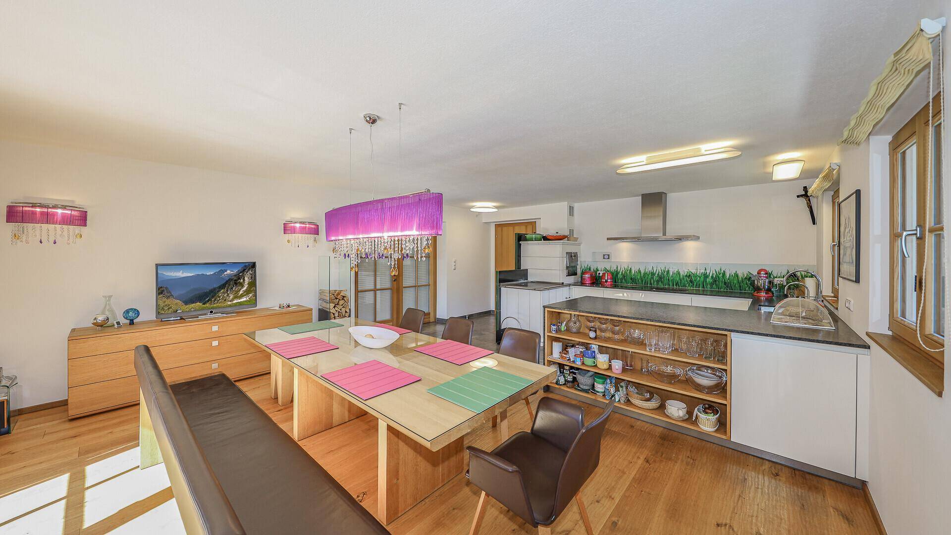 Moderner Wohn-Essbereich mit Holzboden, Esstisch und offener Küche im Hintergrund.