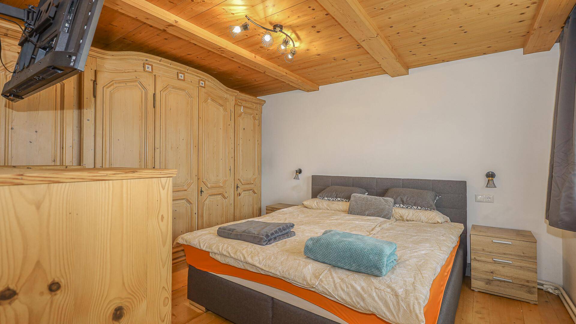 Schlafzimmer mit Holzbalkendecke, großem Bett und traditionellen Holzschränken.