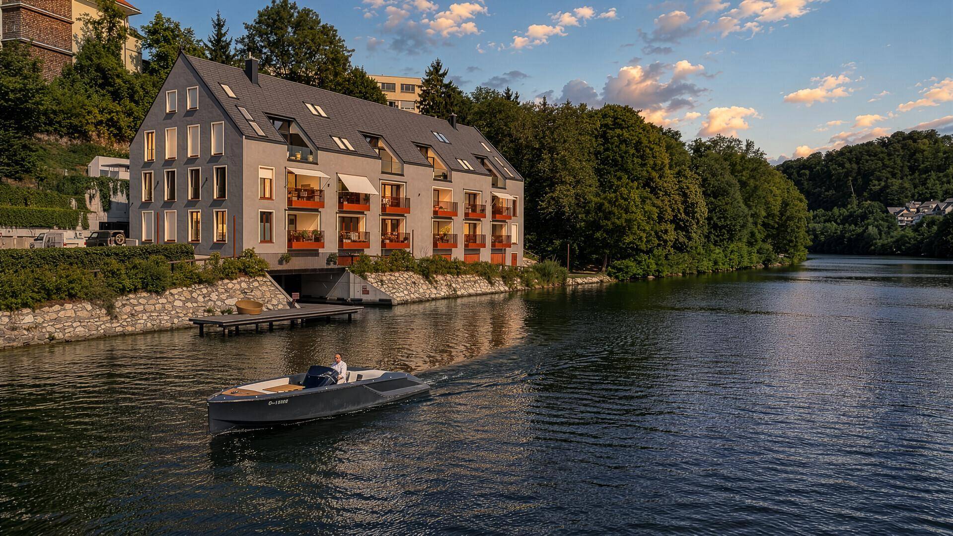 Modernes Apartmentgebäude am Wasser bei Sonnenuntergang, mit Boot und idyllischer Umgebung.
