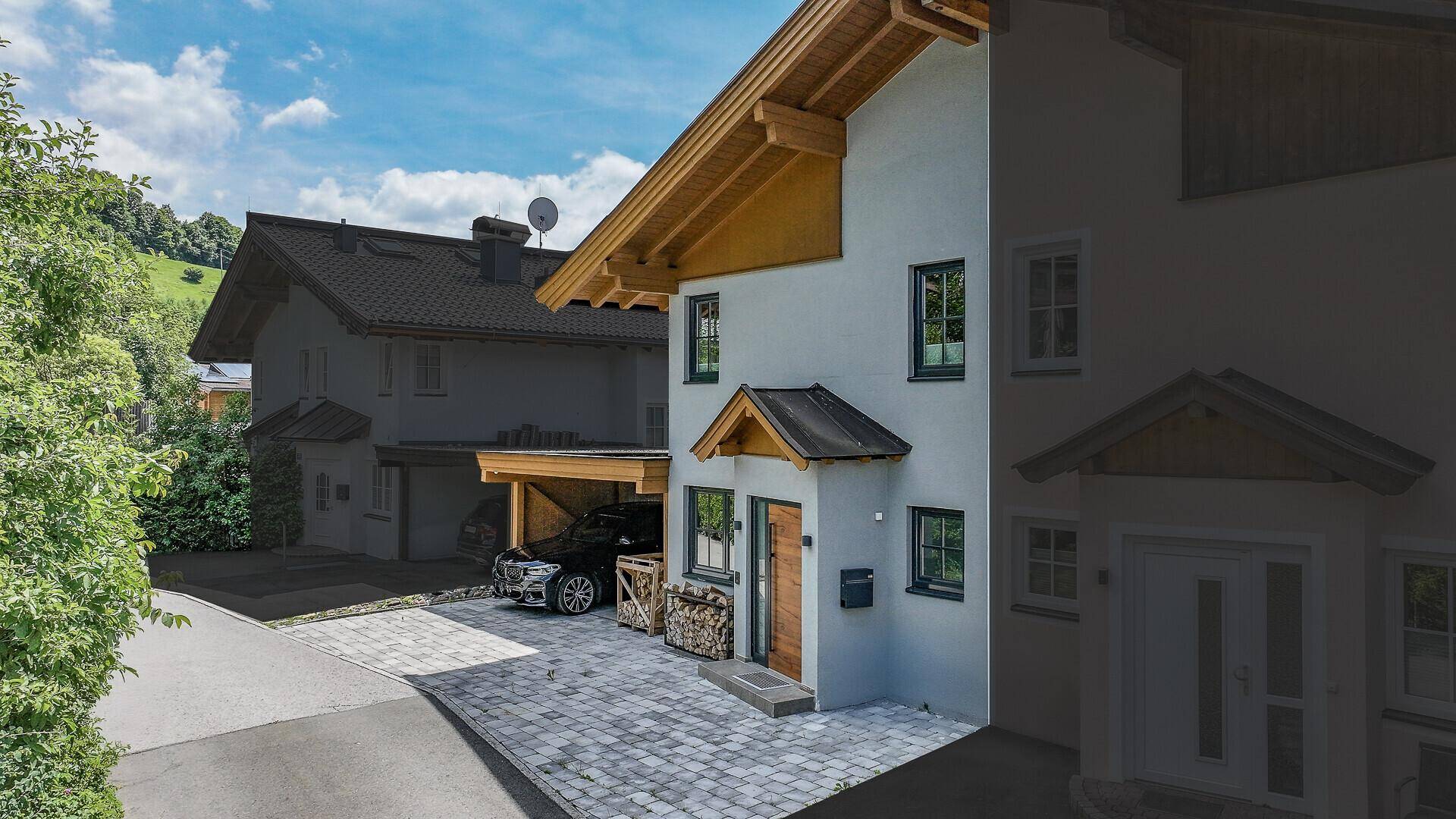 Neubau-Einfamilienhaus mit Carport und gepflastertem Vorplatz in einer ruhigen Wohngegend.