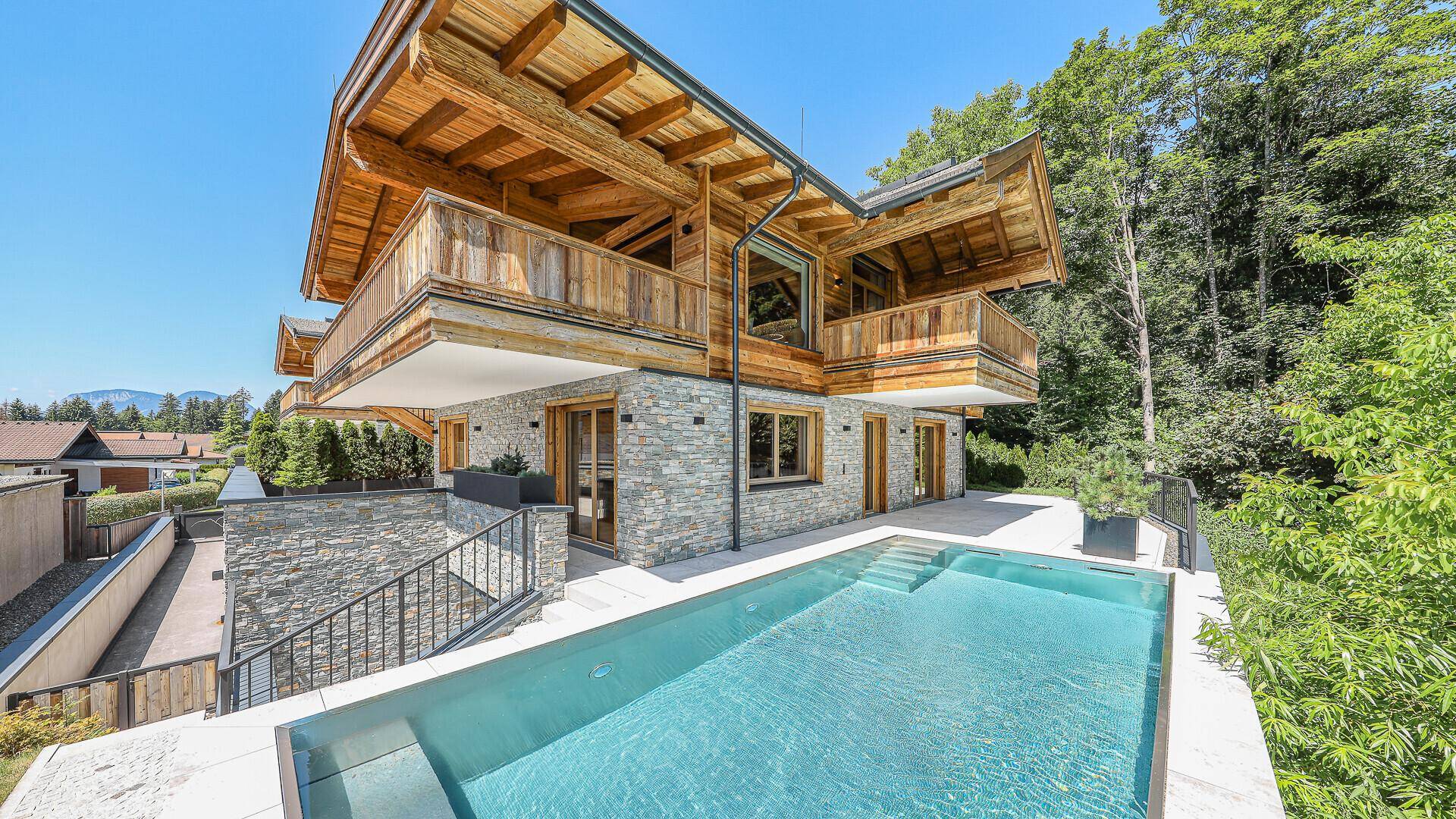 Frontansicht des modernen Chalets mit Holz- und Steinfassade sowie einem einladenden Außenpool.