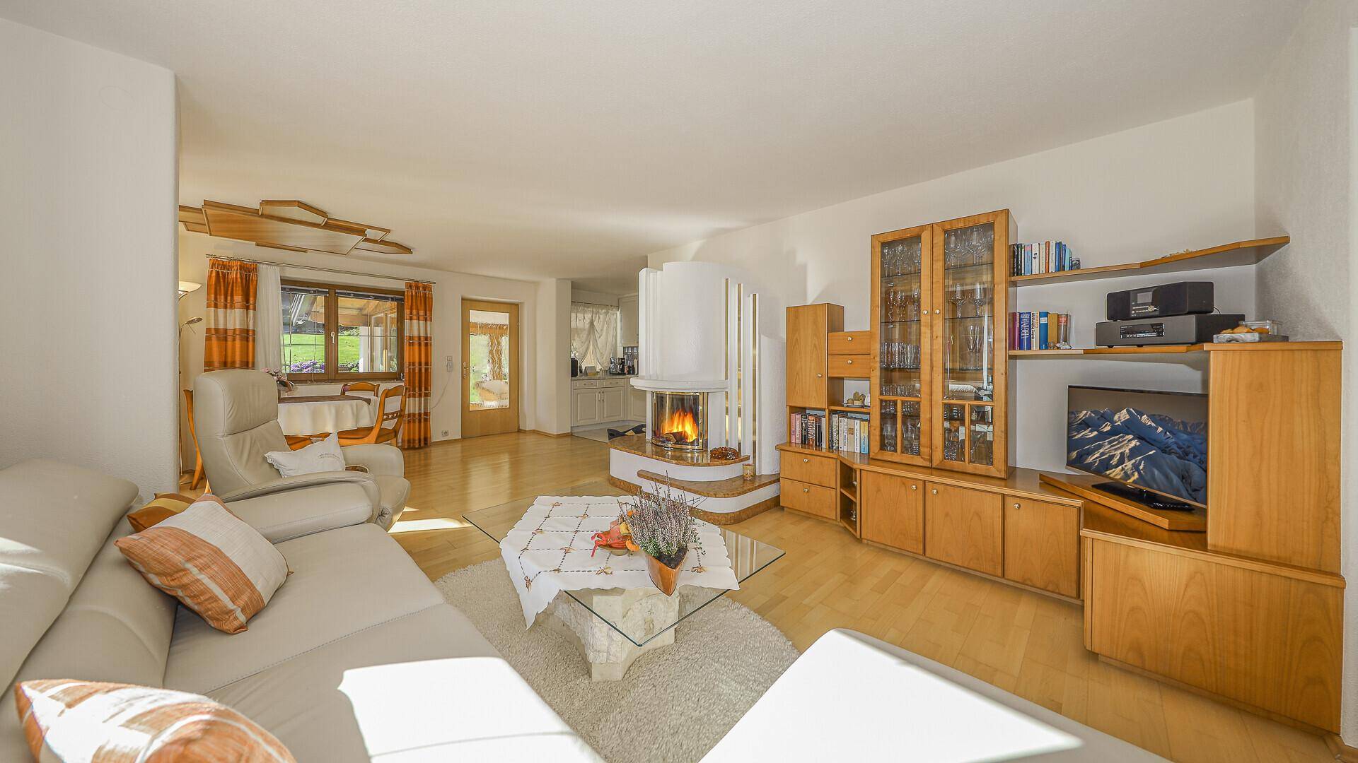 Helles Wohn-Esszimmer mit Kamin, Holzboden und traditionellen Möbeln, offen gestaltet.