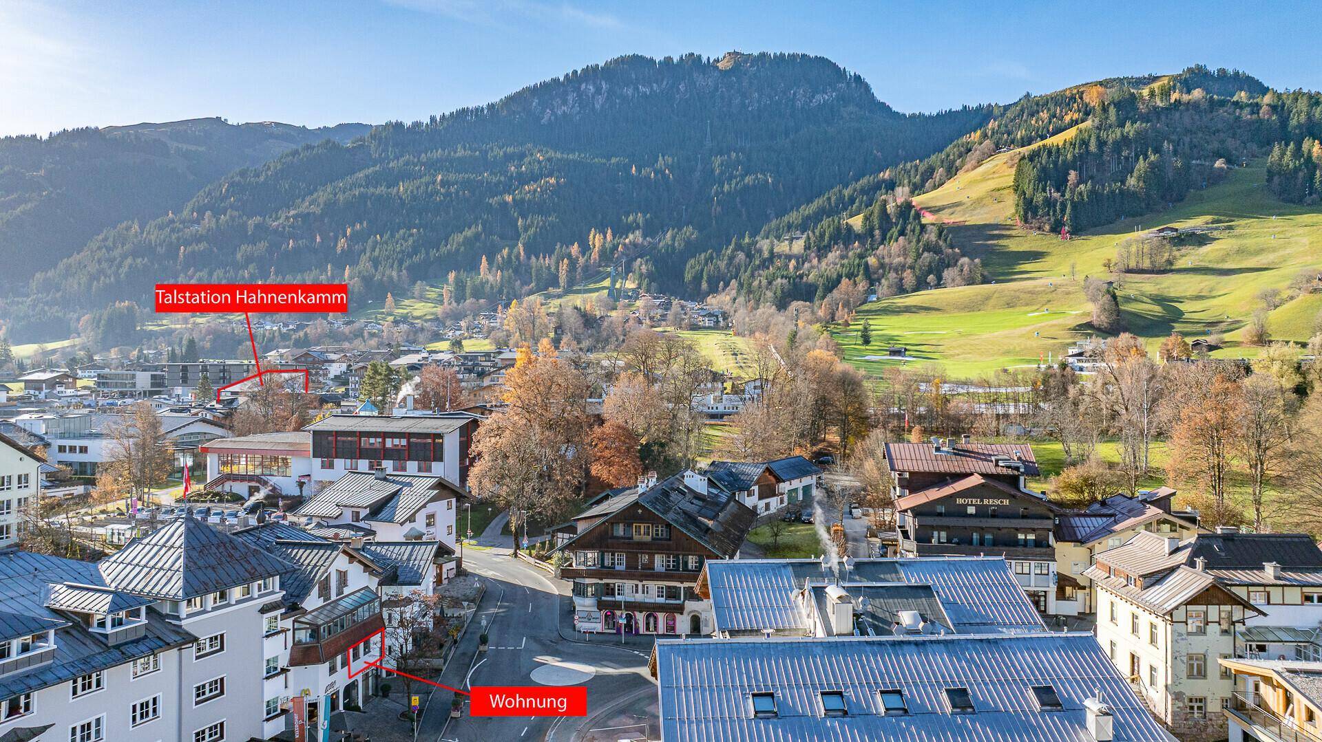 Luftaufnahme der Stadt mit Bergen im Hintergrund und markierten Immobilienstandorten.