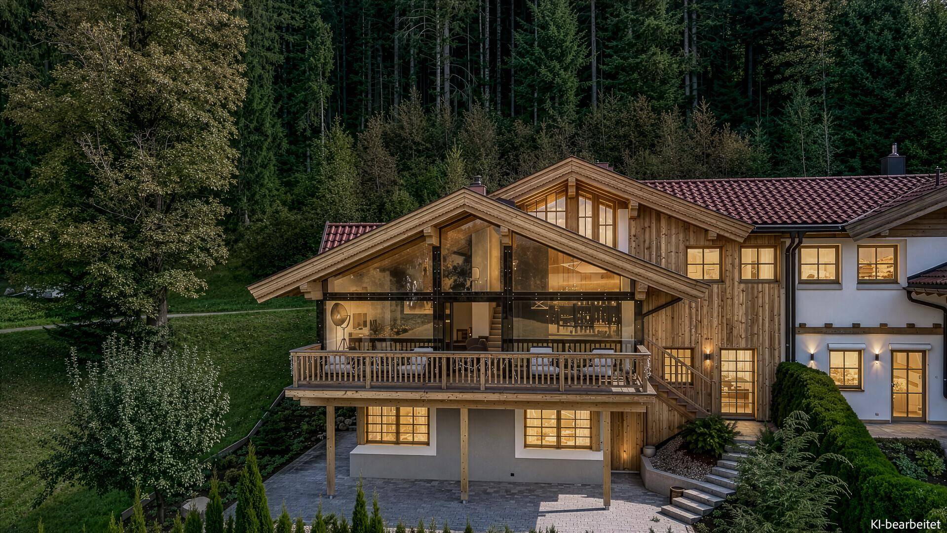 Beleuchtetes Chalet in den Abendstunden mit warmem Licht aus den Fenstern und Balkonen.